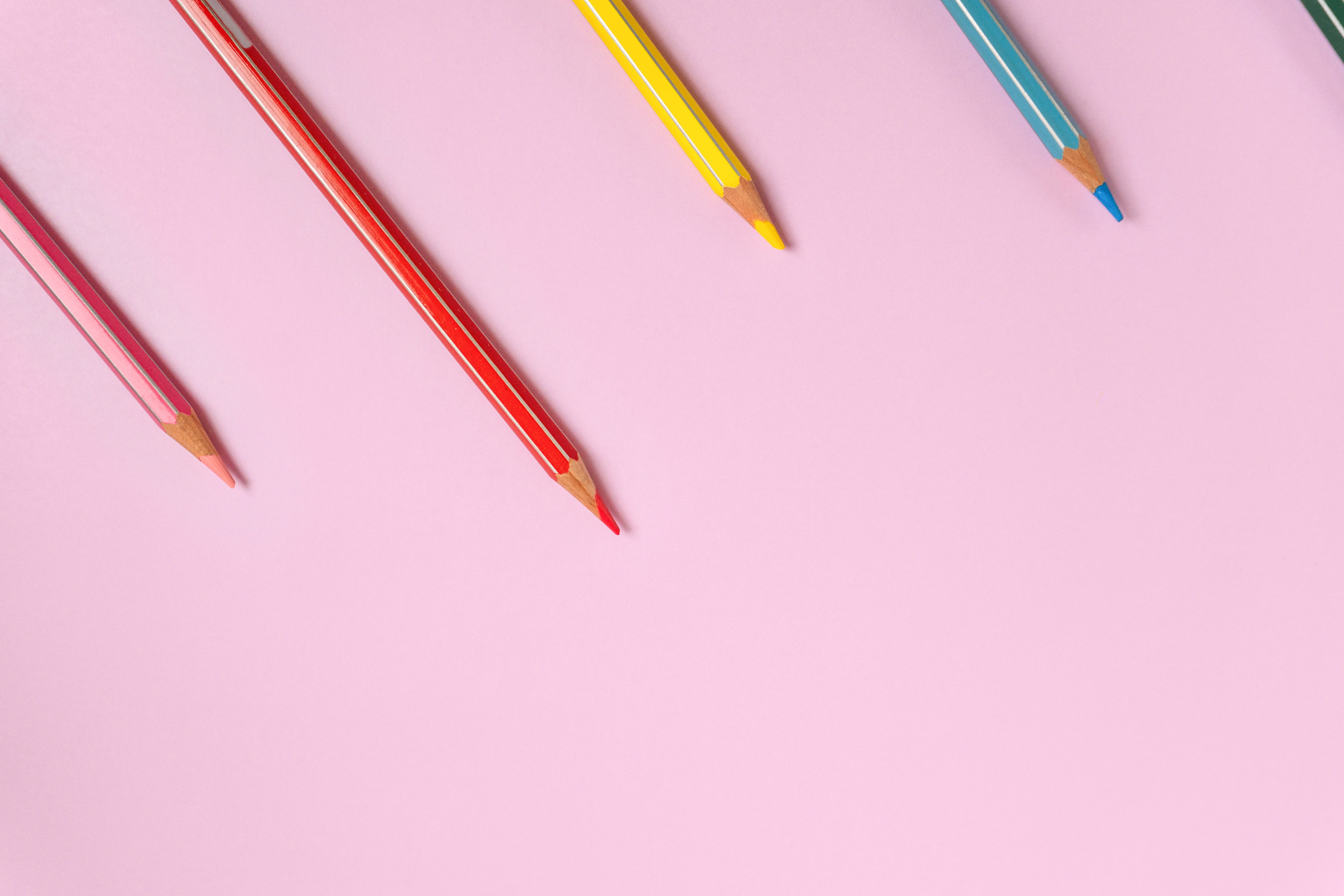 Color pencils on a light pink background. Top view with space for text